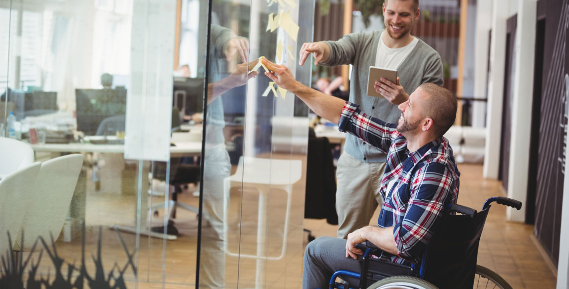 Businessman assisting handicap colleague in creative office