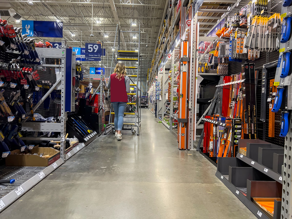Everett, WA USA - circa September 2022: Wide view of a Lowes employee moving a stair ladder around inside the home improvement store.