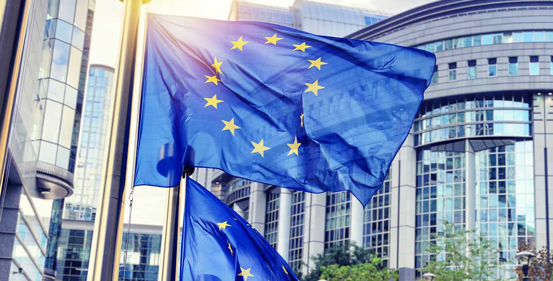 EU flags waving in front of European Parliament building in Brussels