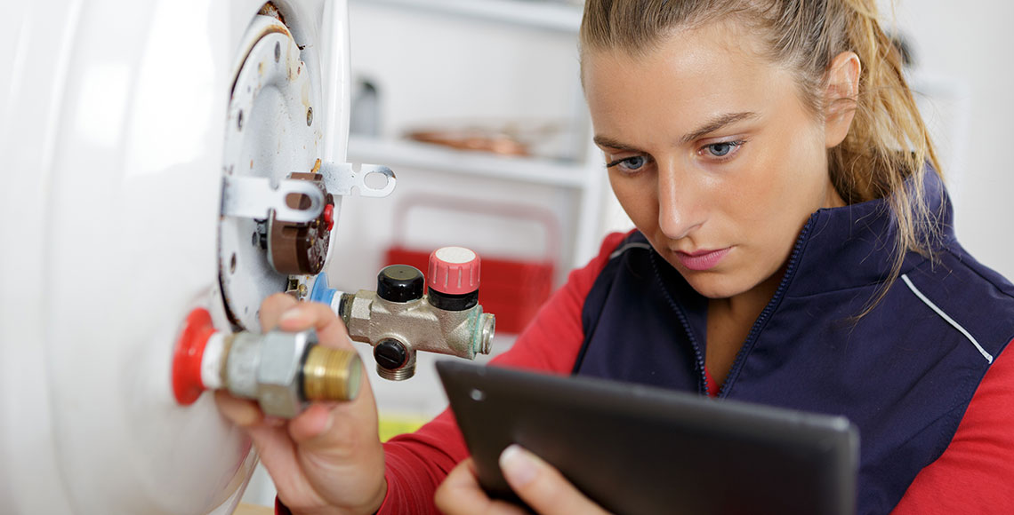 female technician servicing a boiler using tablet computer