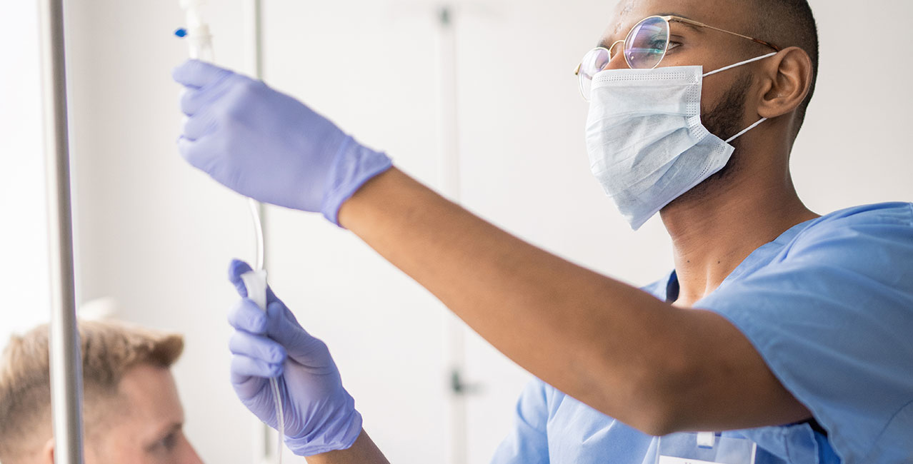 Young mixed-race doctor in uniform preparing dropper for patient in hospital