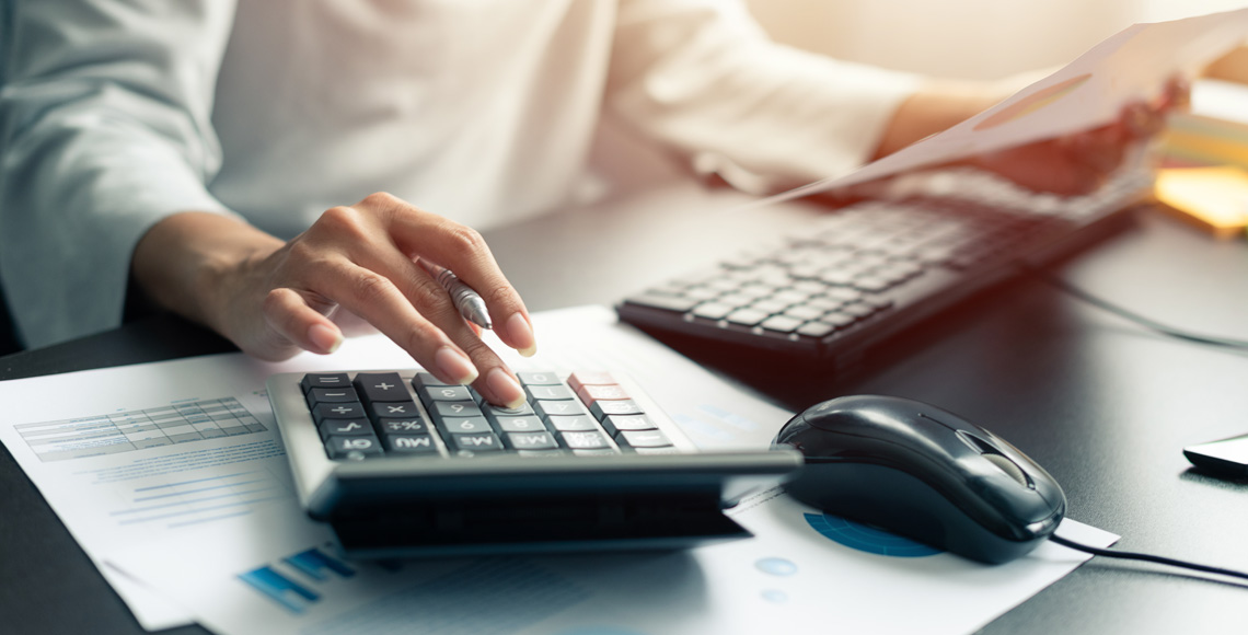 Woman accountant or banker use calculator and computer on table at office