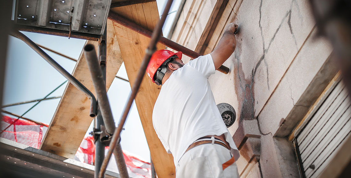 Man worker standing on scaffolding and restore old building facade