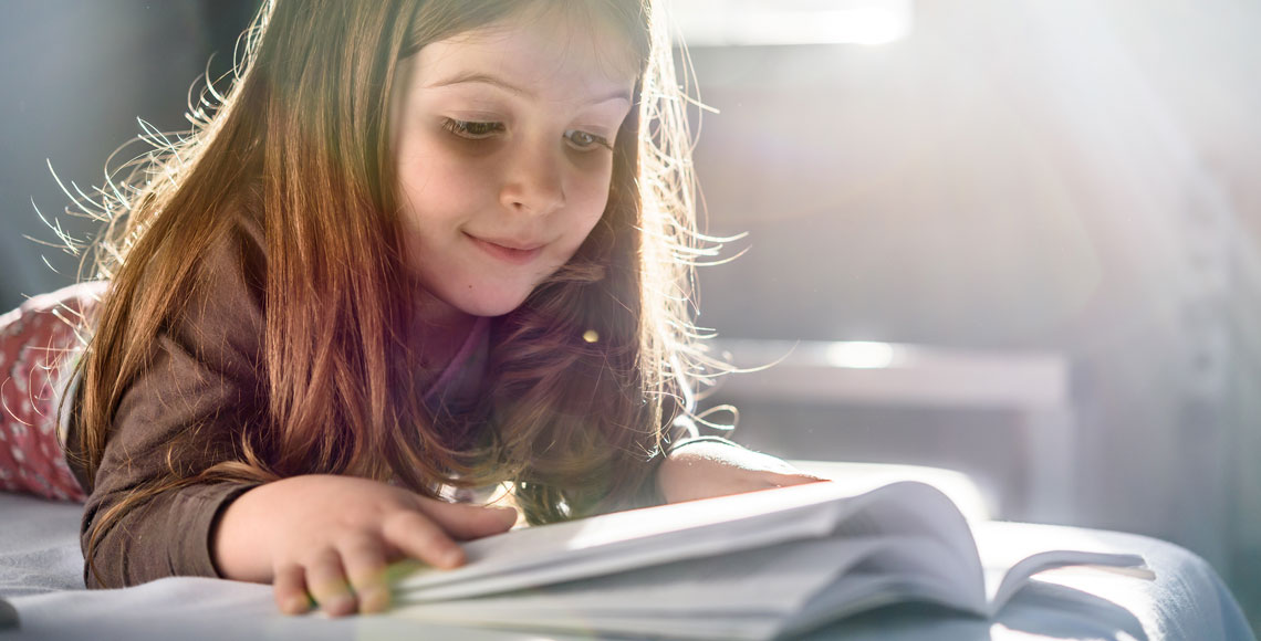 Cute Girl Reading a Book at Home